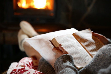 Woman resting with book near fireplace