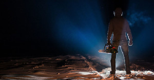 person with a chainsaw standing in low light looking creepy