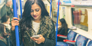 Let's talk about British Indian coming out stories. Image of an Indian woman in a London tube looking at her mobile. 